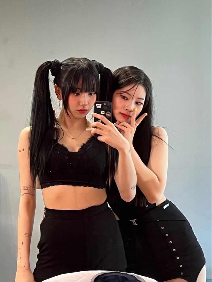 two young women are taking a selfie in front of a mirror while sitting on a bed