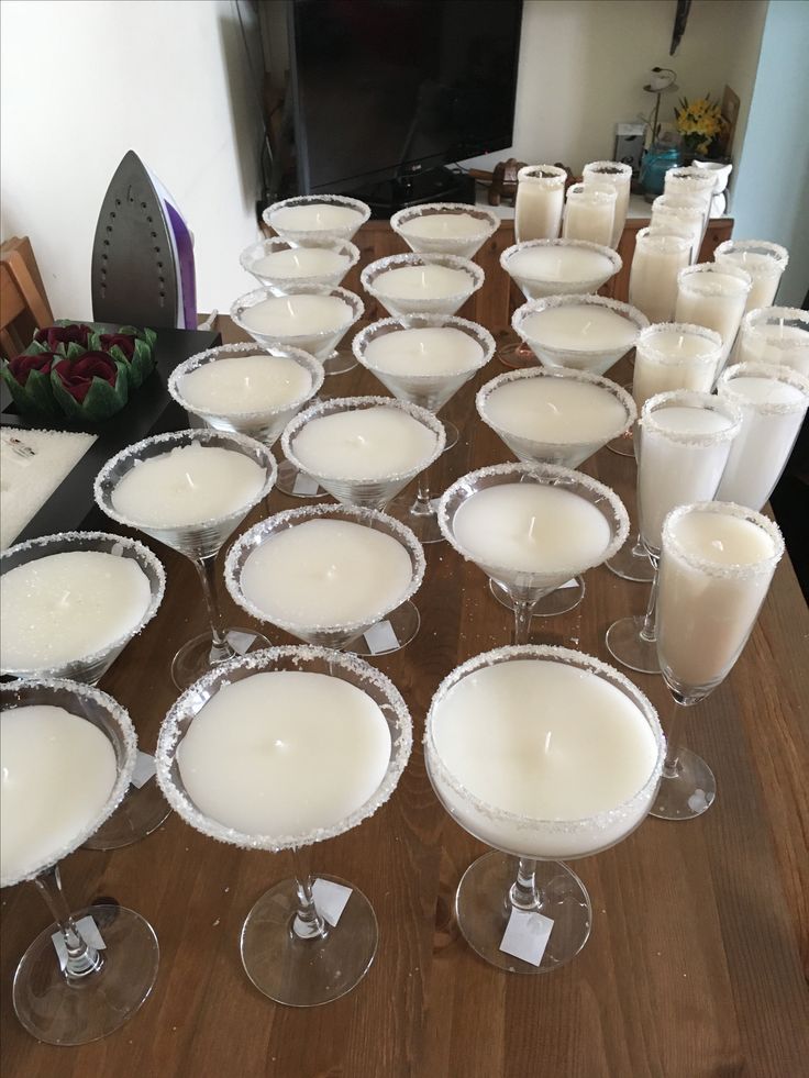 a table topped with lots of glasses filled with liquid and covered in white frosting