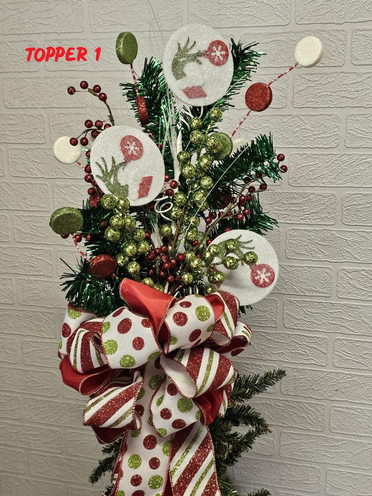 a christmas tree with red and white bows on it's topper is shown in front of a brick wall