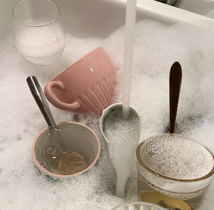 there are some cups and spoons in the bathtub