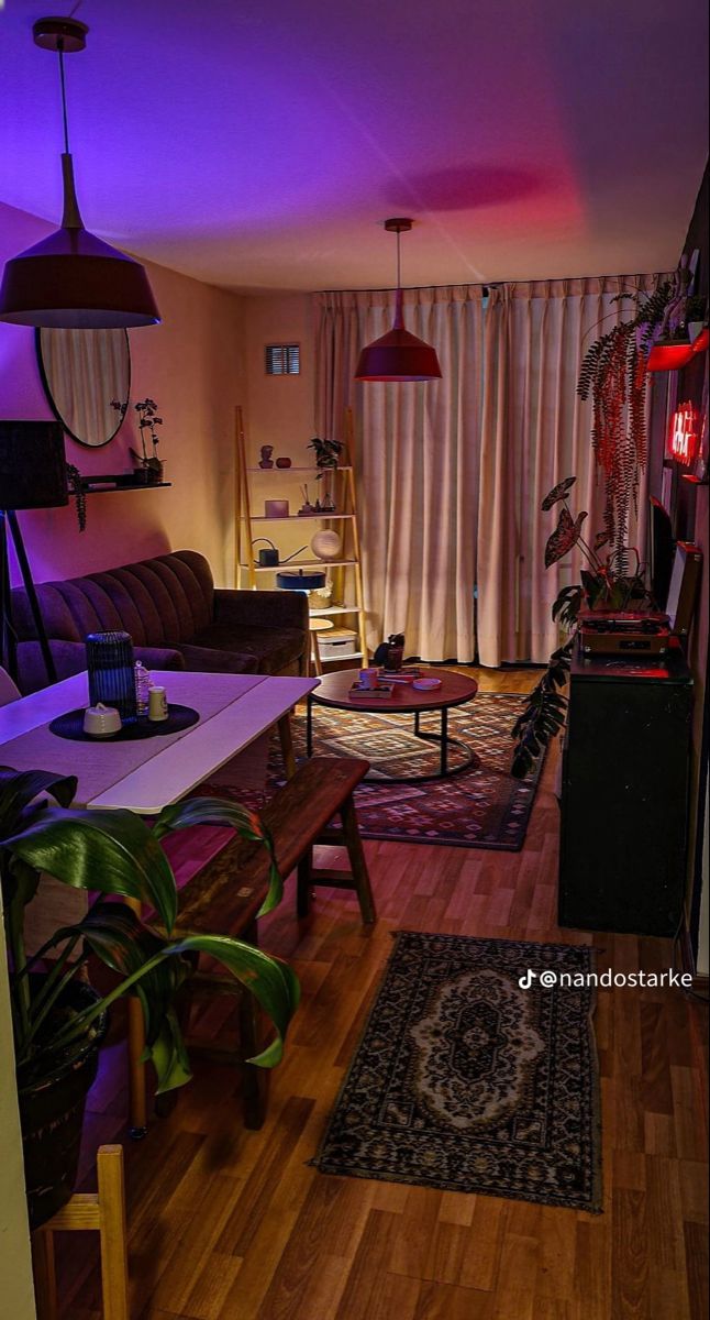 a living room with wooden floors and purple lighting on the ceiling is lit by colorful lights