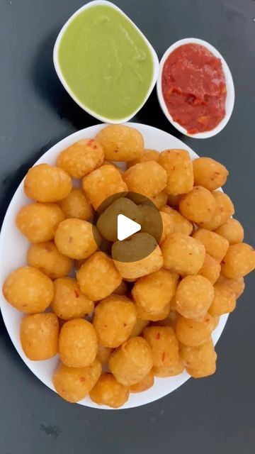 a white plate topped with tater tots next to two small bowls filled with sauce