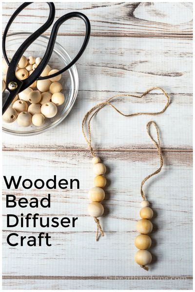 wooden bead diffuser craft with scissors and bowl of beads on white wood background