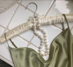 a bra with pearls hanging from it's back on a tile floor next to a wedding garter