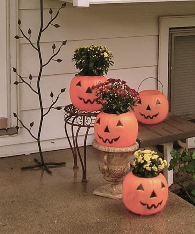 three pumpkin planters with flowers in them on a porch