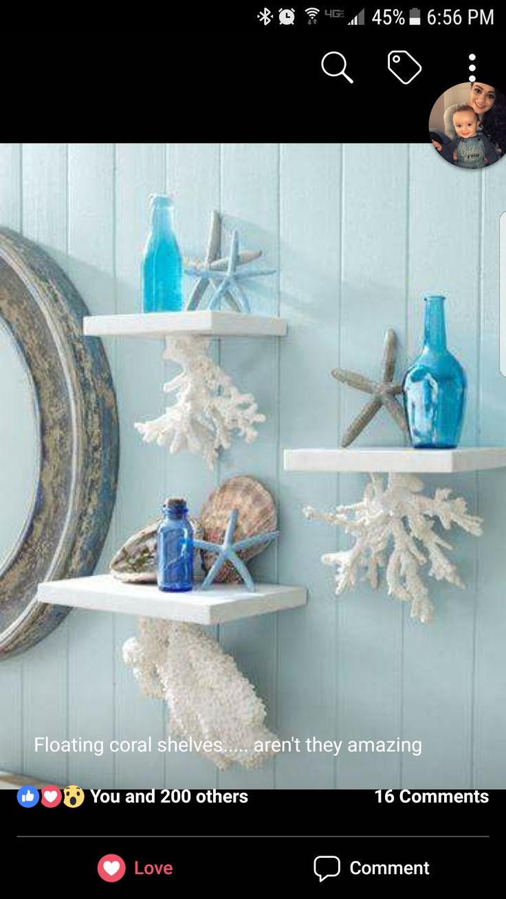 three white shelves with blue bottles and seashells on them, hanging from the wall