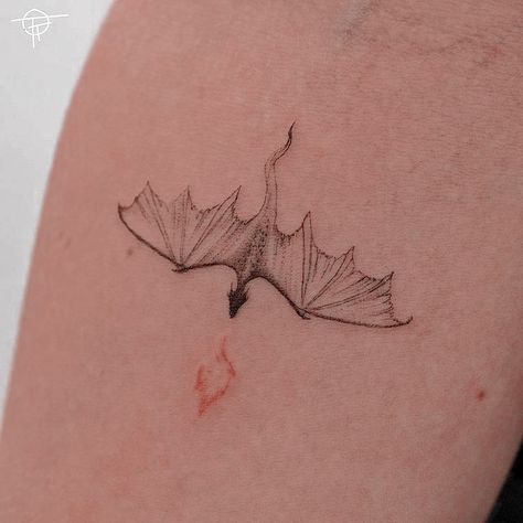 a small tattoo on the back of a woman's left arm, with a bird flying over it