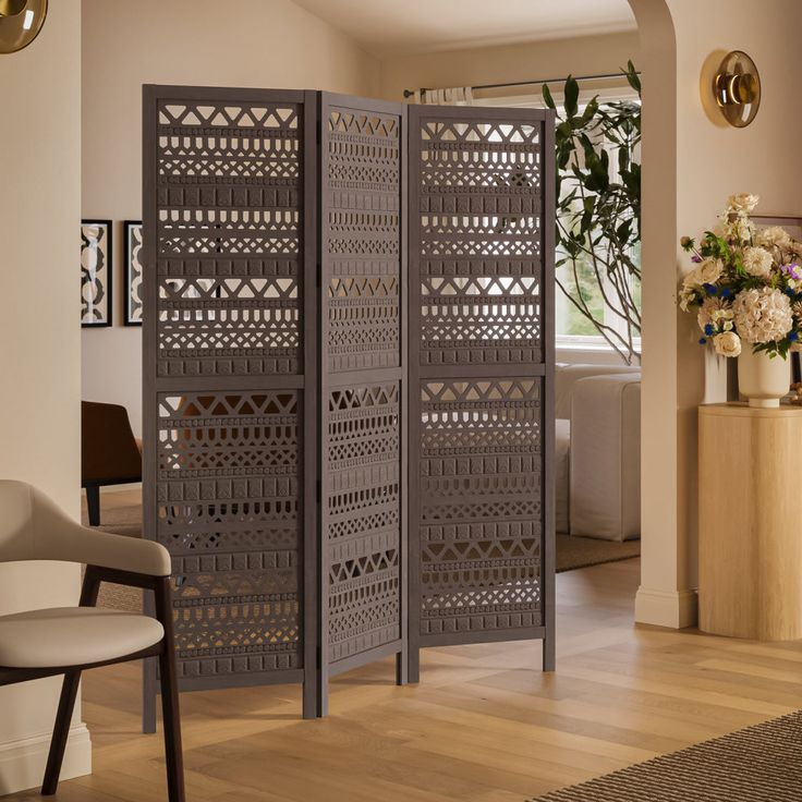 a room divider in the middle of a living room with flowers on the table