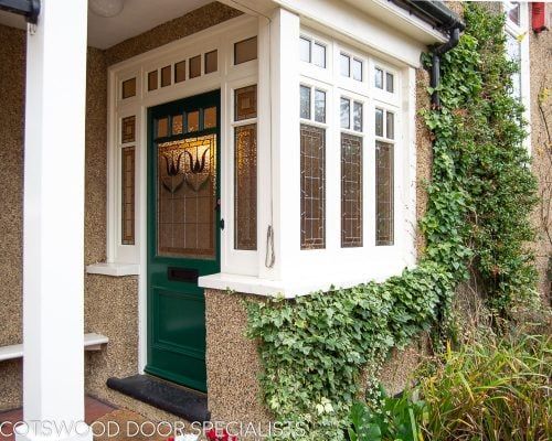 a green door is in front of a house with ivy growing up the side of it