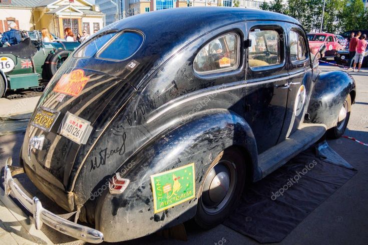 an old black car is parked on the street