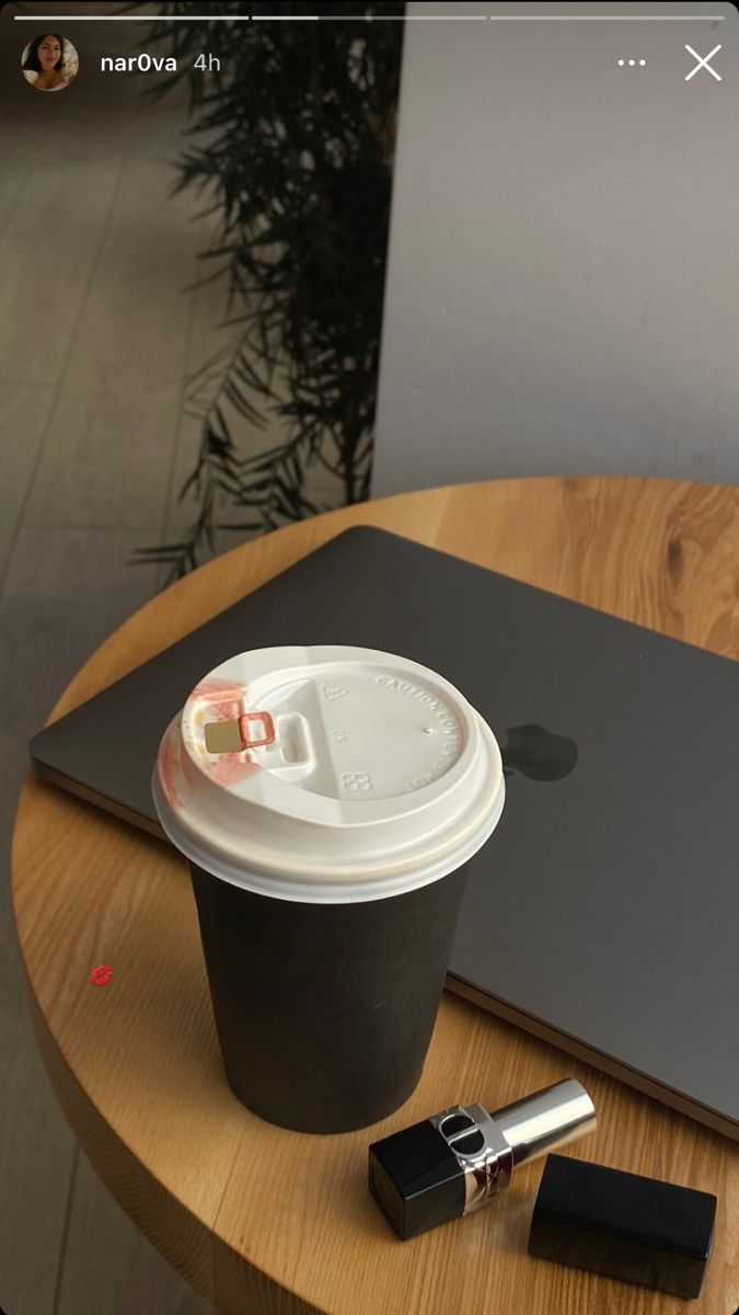 a cup of coffee sitting on top of a wooden table next to a laptop computer