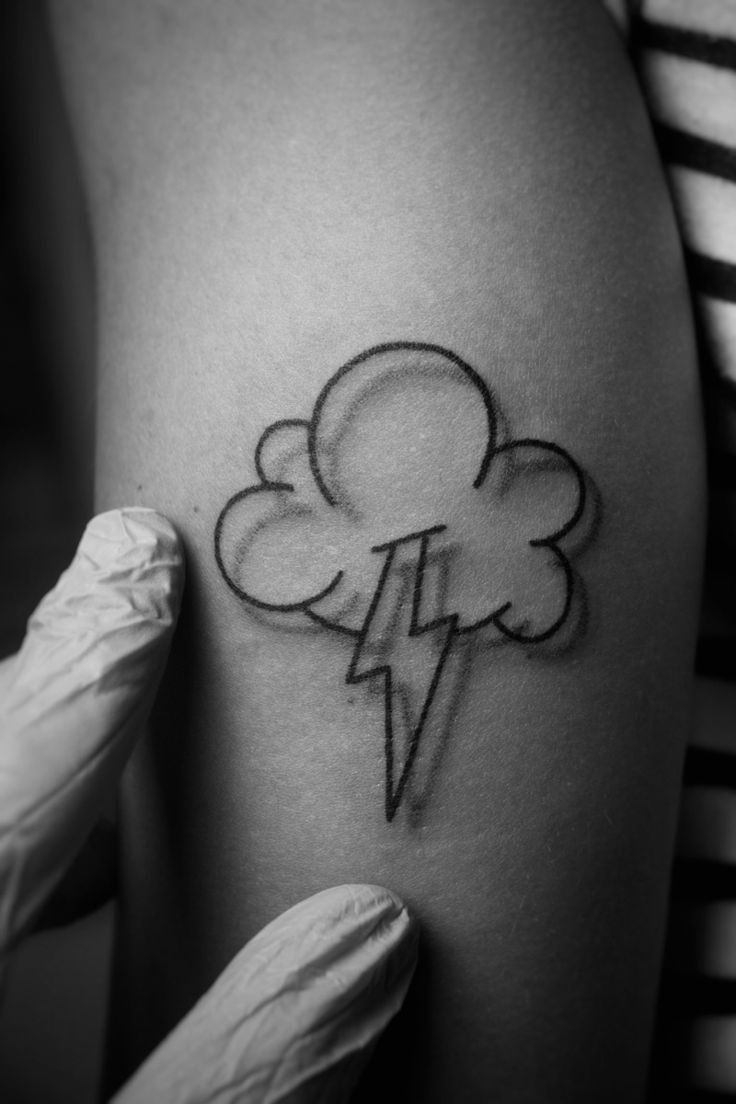 a black and white photo of a woman's arm with a cloud and lightning tattoo on it