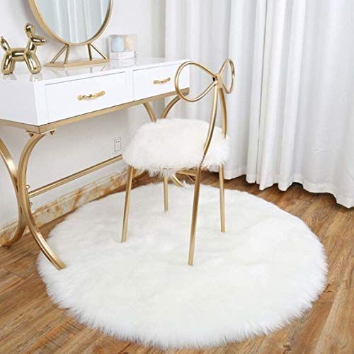 a white chair sitting in front of a mirror on top of a wooden floor next to a desk