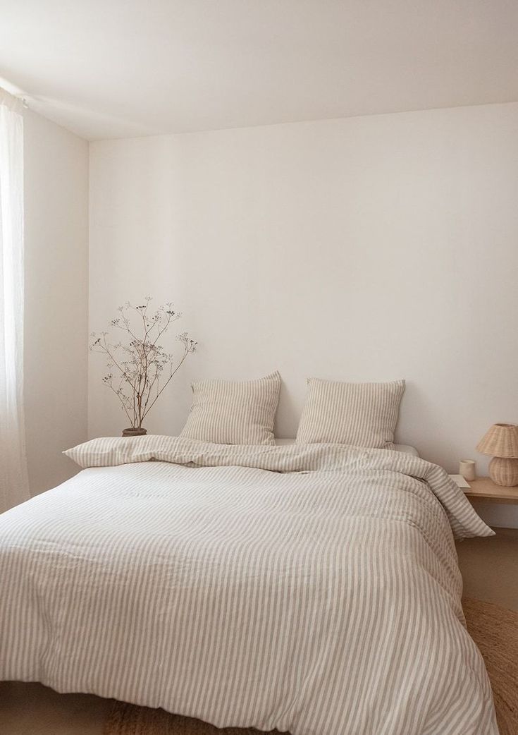 a bed with white sheets and pillows next to a window