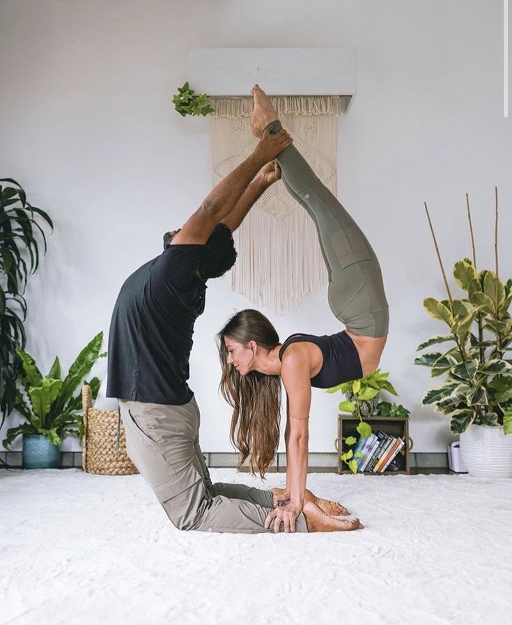 a man and woman are doing yoga on the floor in front of a potted plant