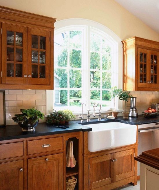 a kitchen with wooden cabinets and black counter tops, along with a large window over the sink