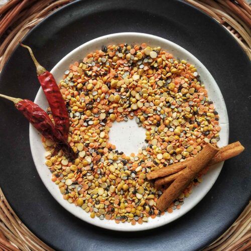 a white plate topped with corn on top of a table next to a red pepper