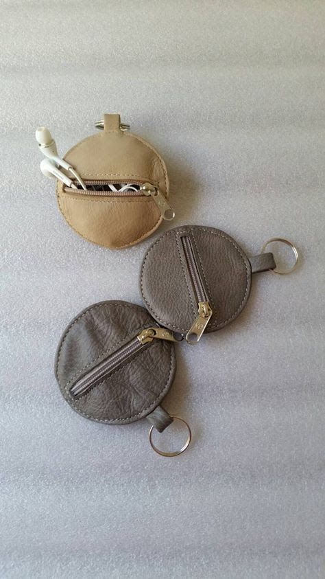 two coin purses sitting on top of a white sheet with silver zipper pulls attached to them