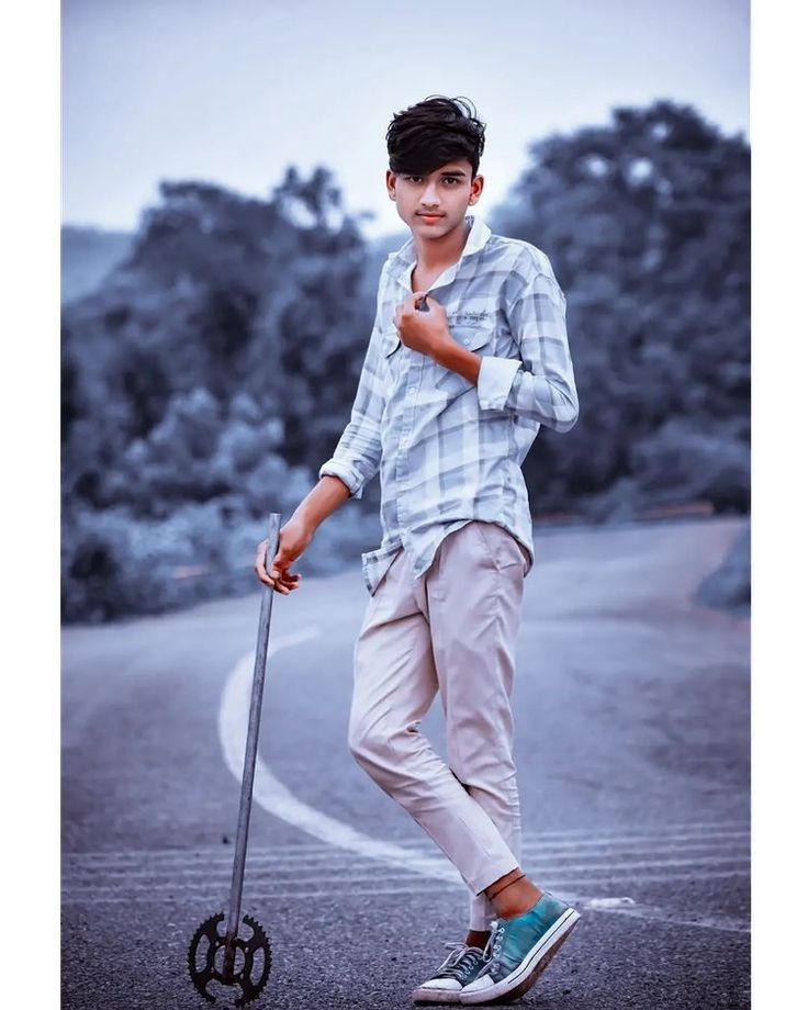 a young man standing on the side of a road next to a metal pole with an umbrella