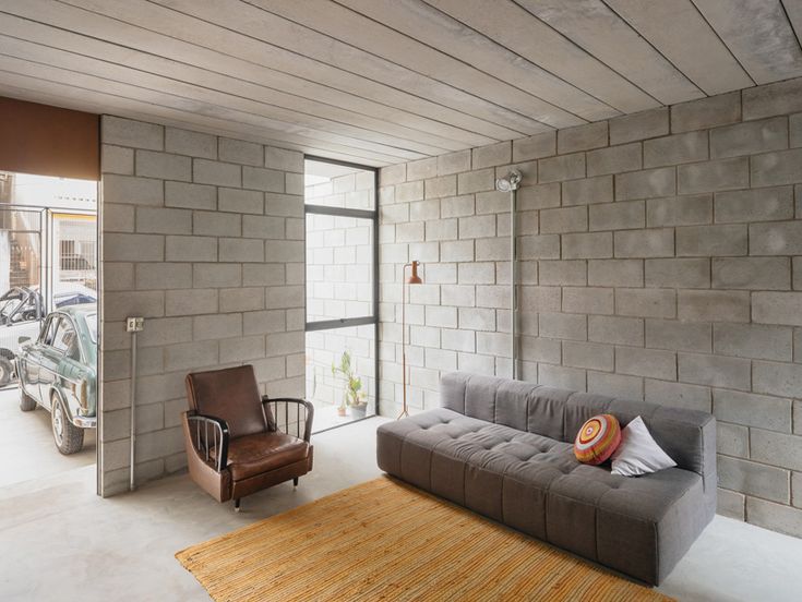 a living room filled with furniture and a large brick wall next to a doorway that leads to a parking lot