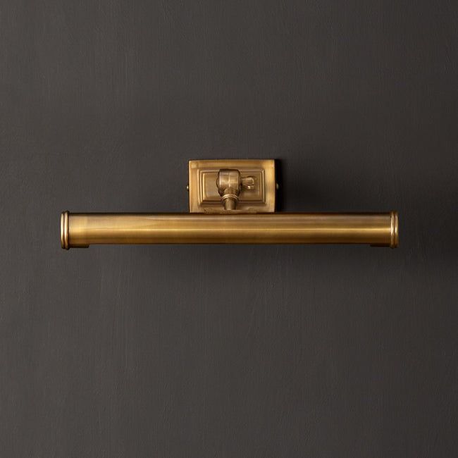 an old fashioned brass toilet roll holder on a gray wall with a black back ground