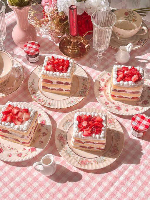 a table topped with plates and cakes covered in frosting on top of a pink checkered table cloth