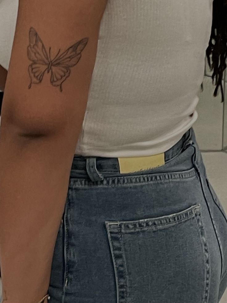 a woman with a butterfly tattoo on her left arm and right arm behind her back