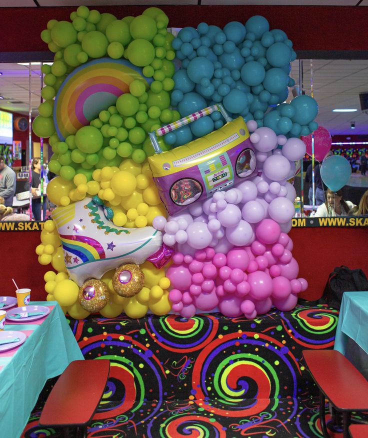 there are many balloons in the shape of cars and rainbows on display at this party