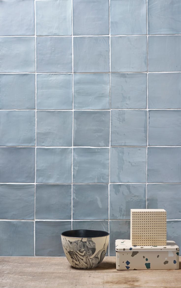 a bowl and speaker on a table in front of a blue tile wall