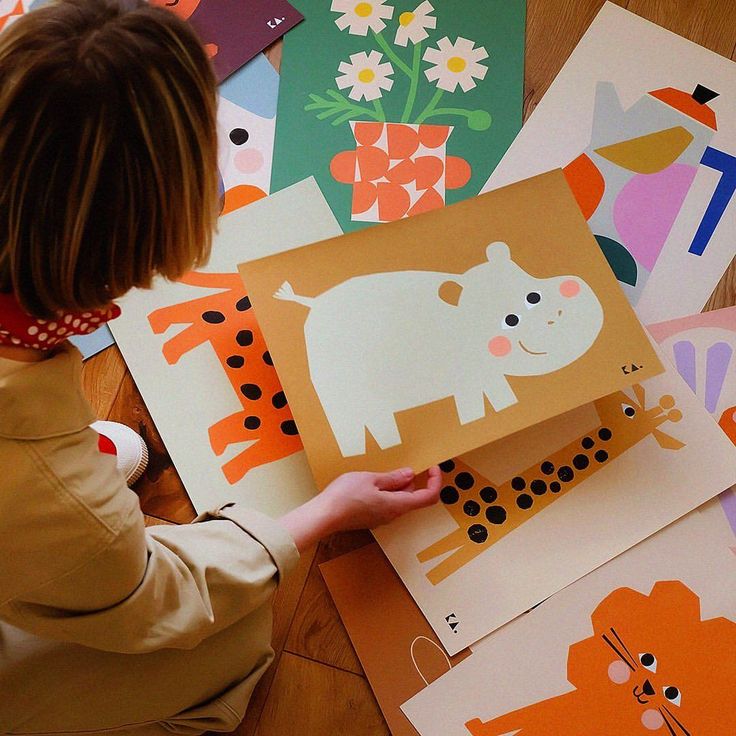 a young child is holding up some paper cut outs with animals and flowers on them