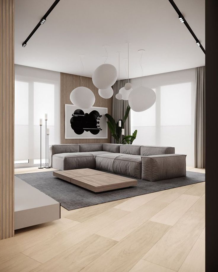 a modern living room with wood flooring and large gray sectional sofa in the center