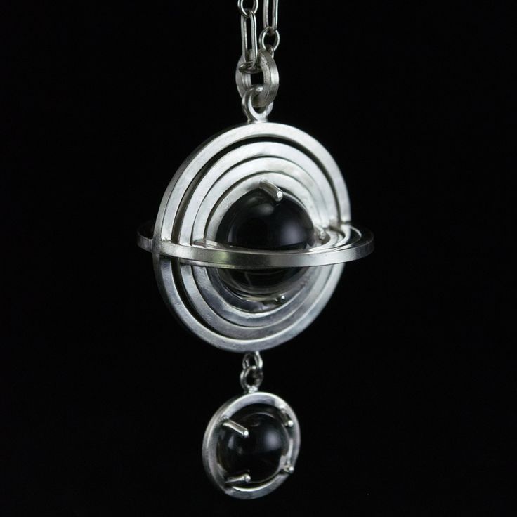 Hand fabricated from sterling silver, nesting 3 dimensional sphere frames turn freely inside one another in four layers. At the core, a 10mm natural and untreated rock crystal ball is contained - able to rotate but not escape. Below the geometric knot, a single 7mm quartz sphere is clutched in a four pronged setting. The pendant is inspired by planetary bodies, motion, and atmospheres. Measuring just under 1 inch across and just over 1.5 inches long, each pendant comes strung on a 24" sterling s Contemporary Silver Jewelry With Gemstone, Elegant Silver Orb Jewelry, Silver Orb-shaped Metal Jewelry, Modern Spiral Jewelry For Formal Events, Modern Spiral Jewelry For Formal Occasions, Unique Silver Orb-shaped Jewelry, Sterling Silver Sphere-shaped Jewelry, Modern Round Jewelry With Unique Variations, Handmade Elegant Spherical Jewelry