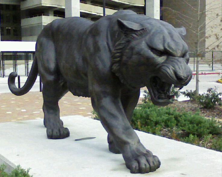 a statue of a large black tiger in front of a building with its mouth open