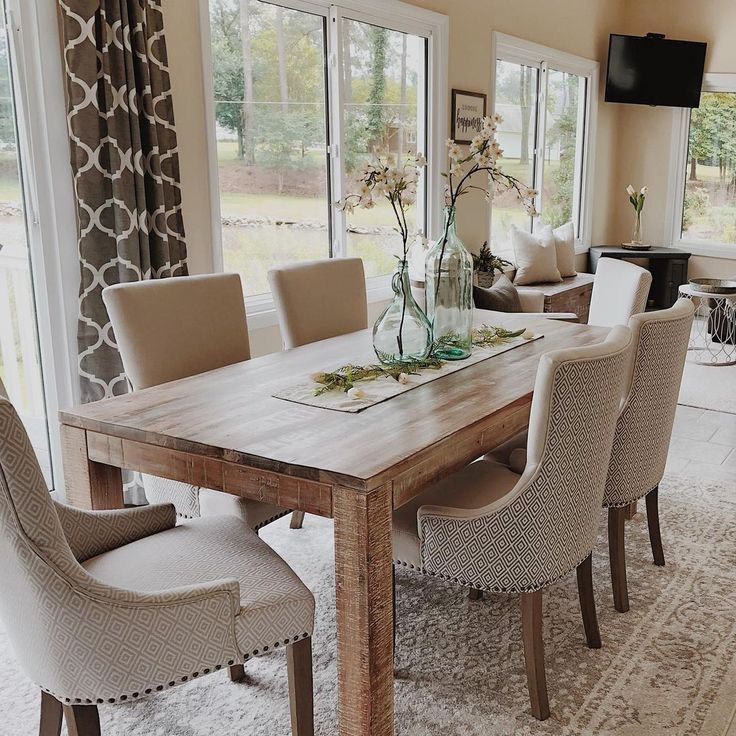 a dining room table surrounded by chairs and windows