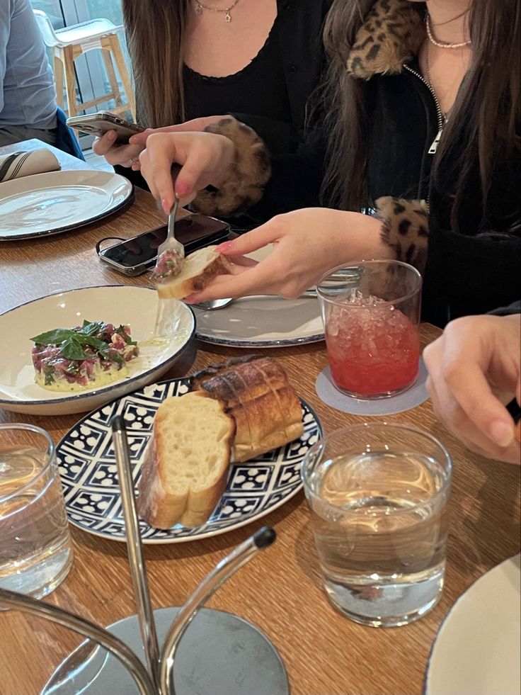 two women sitting at a table with plates of food and drinks in front of them