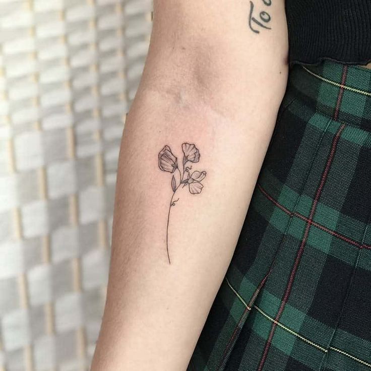 a woman's arm with a single flower tattoo on the left side of her arm