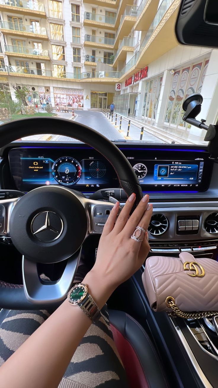 a woman driving a car with her hand on the steering wheel and holding onto an armband