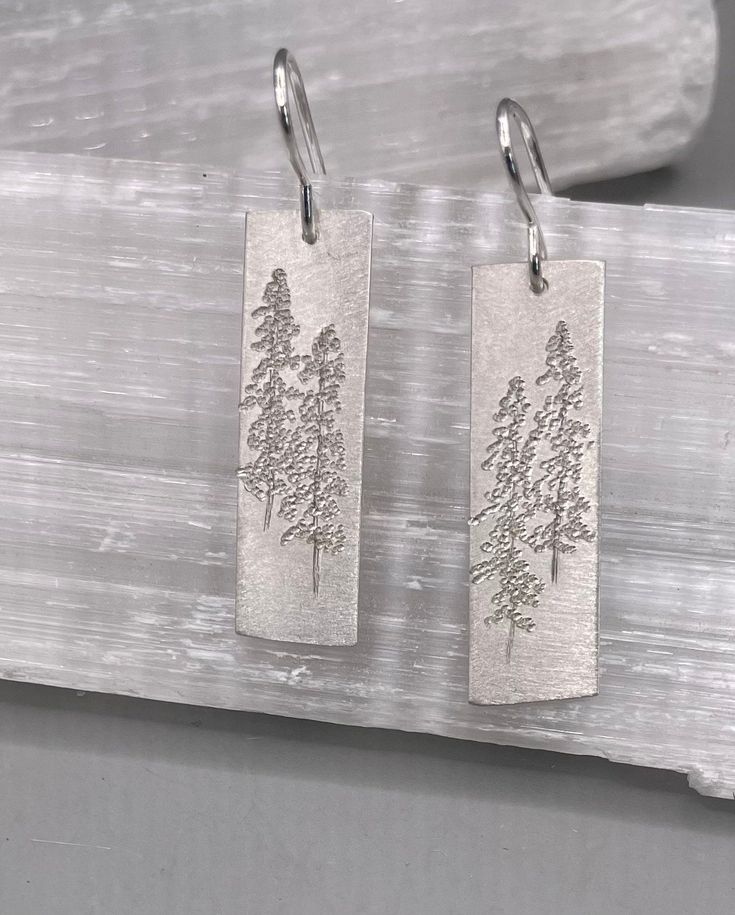 "Large sterling silver Tall Pine Earrings etched with Lodge Pole Pines. The earrings dangle from sterling silver French wires and measure 1 1/8\" x 3/8\"." Silver Etched Earrings As A Gift, Silver Stamped Earrings For Everyday, Silver Etched Earrings For Gifts, Everyday Silver Stamped Earrings, Elegant Stamped Earrings As Gift, Engraved Sterling Silver Adjustable Earrings, Etched Sterling Silver Dangle Earrings, Silver Etched Dangle Jewelry, Dangle Etched Earrings As Gift