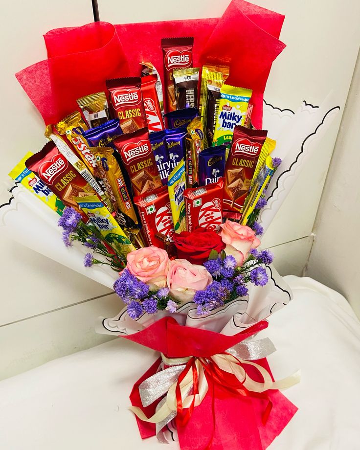 a bouquet of chocolates and flowers on a bed