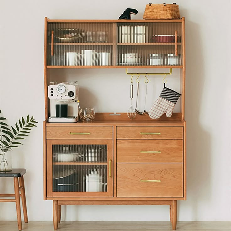 a wooden cabinet with glass doors and shelves above it, next to a small chair