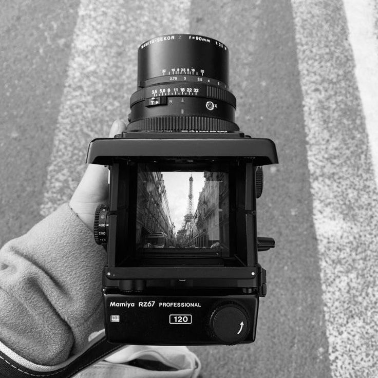 a person is holding up a camera to take a photo on the street with buildings in the background