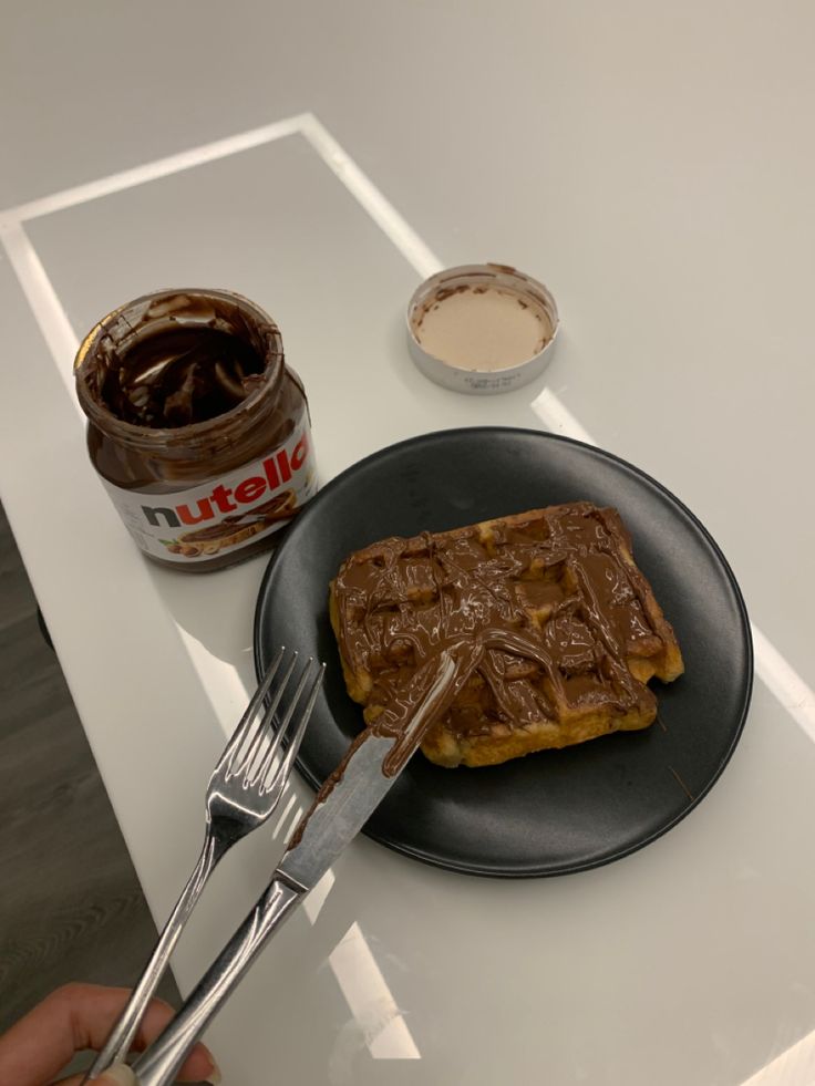 a waffle on a plate with a fork next to it and some peanut butter