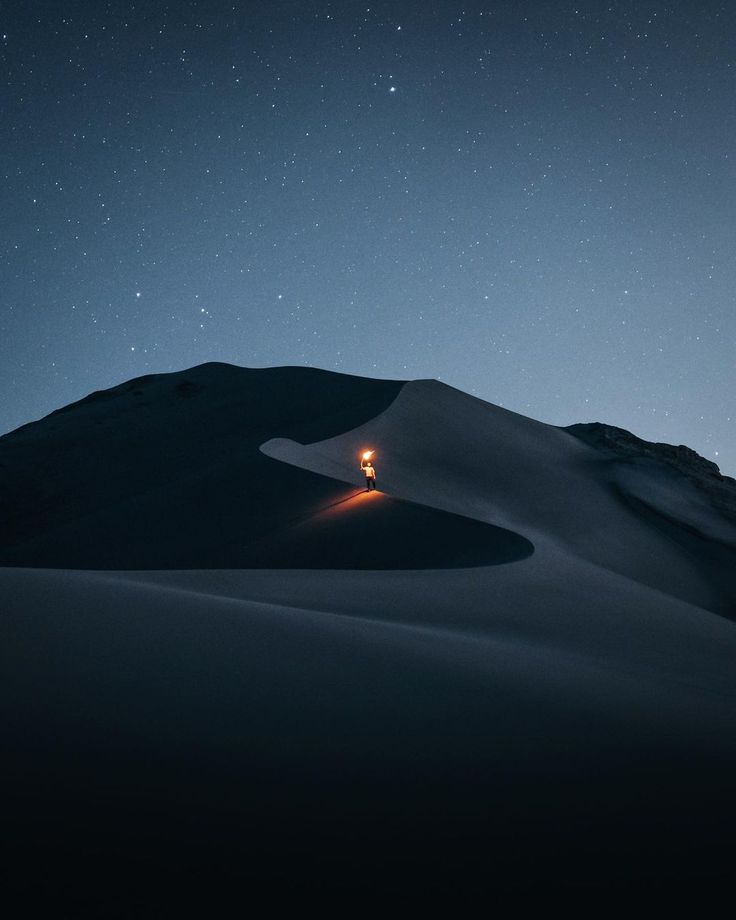 a person standing in the middle of a desert at night