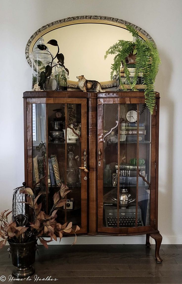 a wooden cabinet with glass doors and plants on top