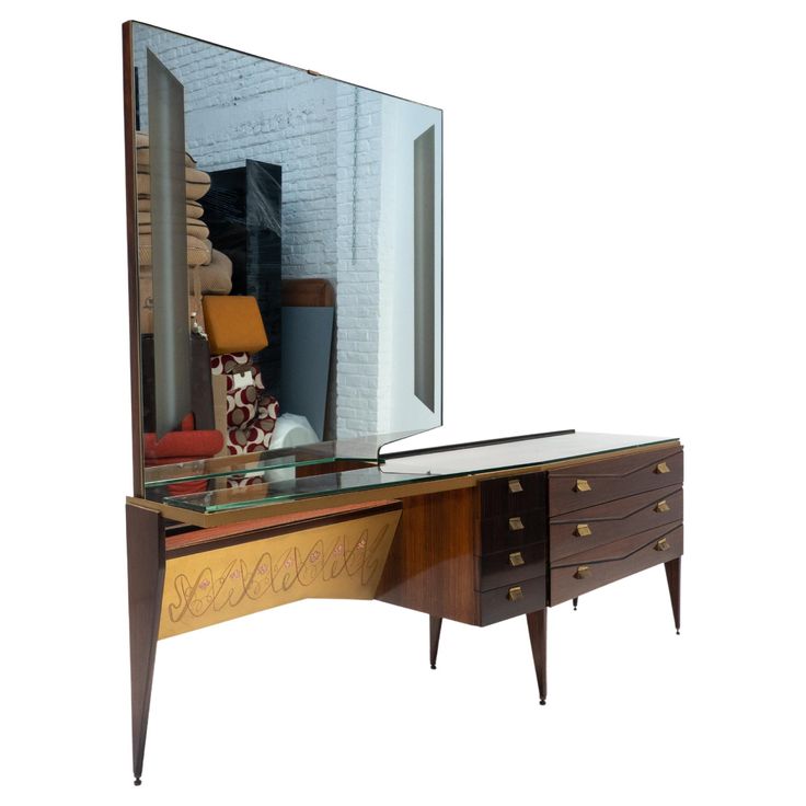 a mirror sitting on top of a wooden dresser next to a table with drawers under it