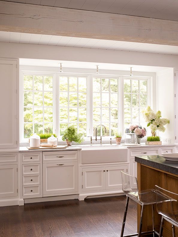 a large kitchen with white cabinets and wooden flooring, along with an island in the middle