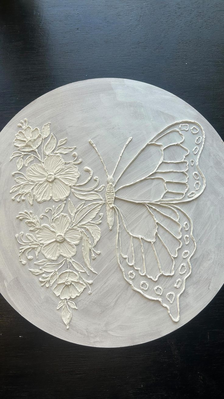 a white plate with a butterfly and flowers carved on the side, sitting on a table