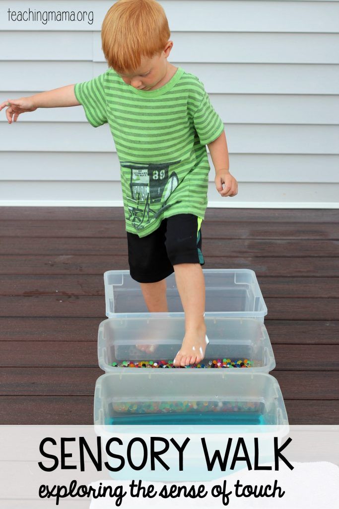 a young boy standing on top of a plastic container filled with water and sand next to a