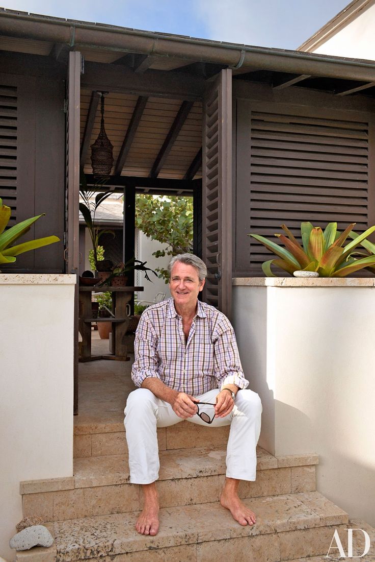 a man sitting on steps in front of a house with potted plants next to him