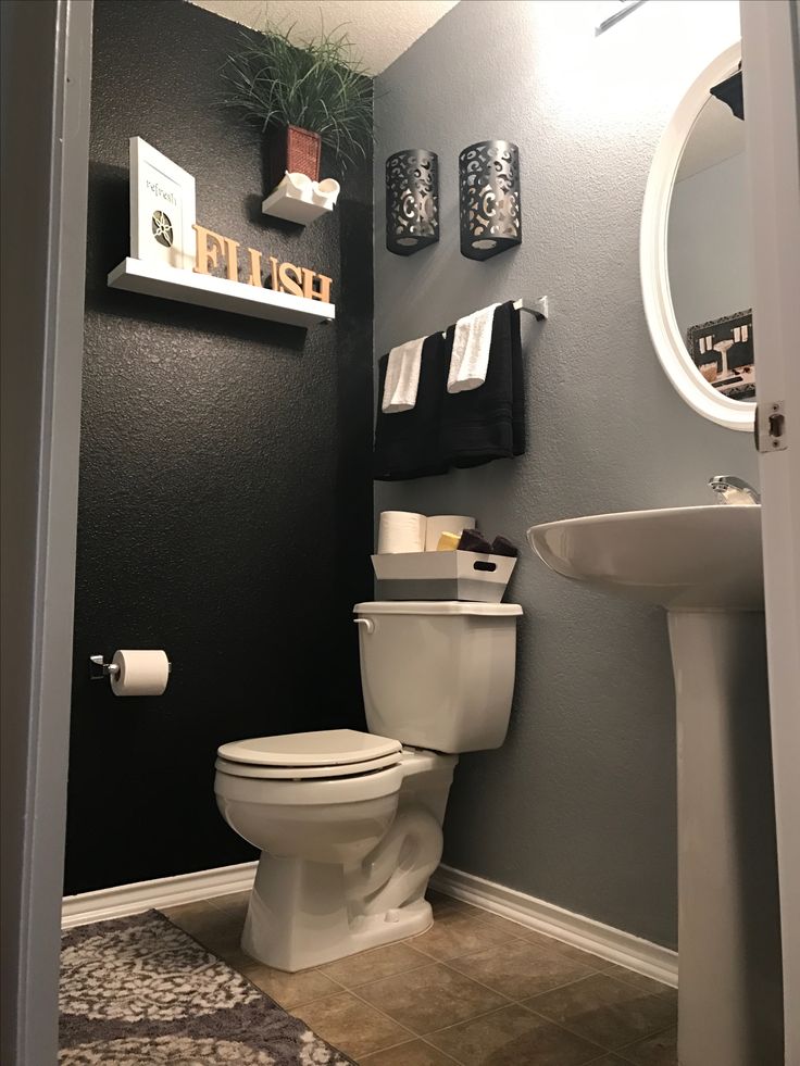 a white toilet sitting in a bathroom next to a sink under a mirror and towel rack